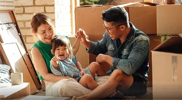 Cheerful middle eastern family with eyeglasses of three having fun together at home. Mixed race parents talking with their little girl in living room. Cheerful family with specs embracing and playing with beautiful indian daughter girl in arms.